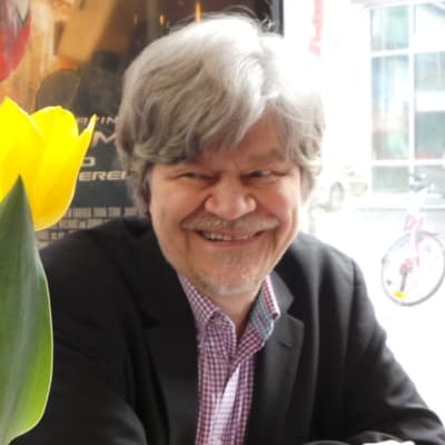 M.A. Numminen istuu pöydän ääressä.