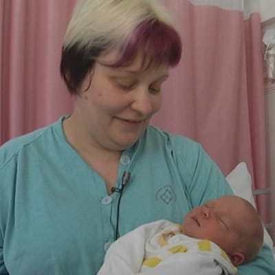 Nainen vauva sylissä synnytyssairaalan osastolla.