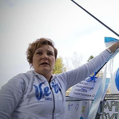 Anne Niemi kiinnittää ilmapalloja kaiteeseen