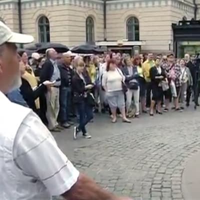 Mielenosoittajia Kolmen sepän patsaalla Helsingissä.