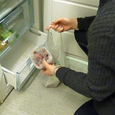 Nainen ottaa pakasteita pakastimesta