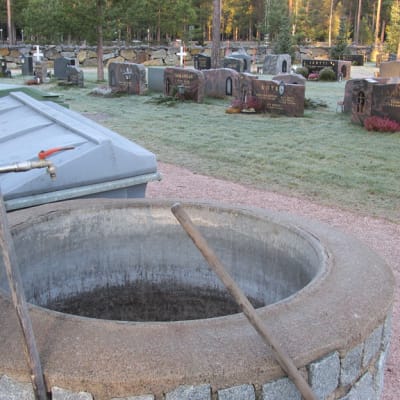 Kuvassa hautausmaa, hautakiviä, vesiäiliö ja jätepönttö