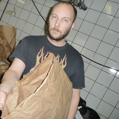 Kuvassa Tomi Karhula pitää kädessään paperisäkistä otettua kuivattua perunaa