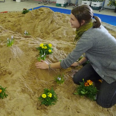 Puutarhurit Mira Korpela ja Johanna Käppi istuttavat samettikukkia purkeissaan hiekkaan