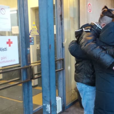 Sangar, Kristina ja Harri halaavat vastaanottokeskuksen ovella