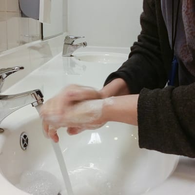 Henkilö pesee käsiään lavuaarissa. 