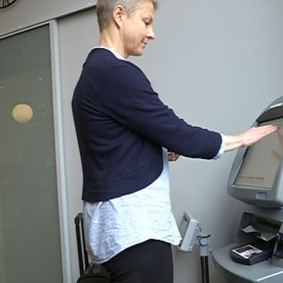 Nainen käyttää nurkassa seisovaa automaattia