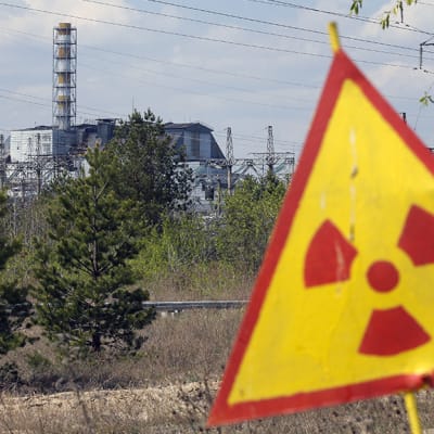 Radioaktiivisuusvaroitusmerrki ja Tsernobylin ydinvoimala-aluetta.