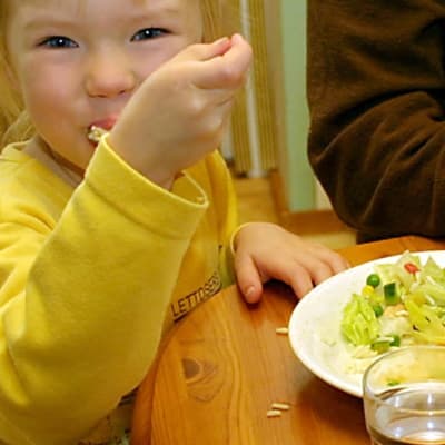 Litet barn stoppar mat i munnen.