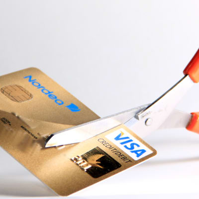 Kuvassa luottokorttia leikataan saksilla. 