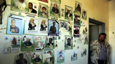 En vägg med bilder på offren för flygräden mot begravningslokalen i Sanaa