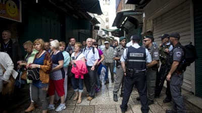 Turister passerar israeliska poliser efter en knivattack i Jerusalem den 7 oktober 2015.
