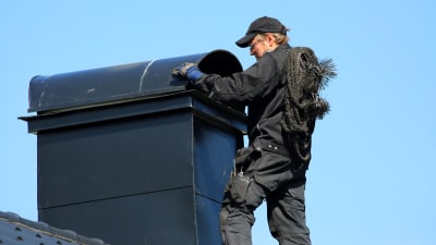 Sotare förbereder sotning av skorsten genom att skjuta undan skyddstak av plåt.