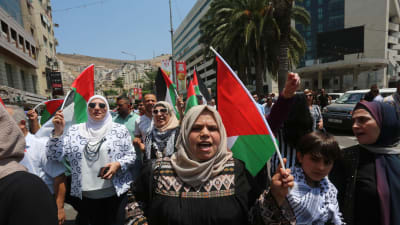Kvinnor och män med palestinska flaggor i händerna demonstrerar i staden Nablus.