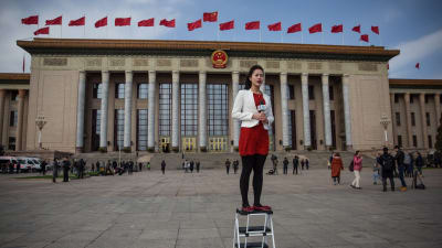 En journalist står på en pall då hon rapporterar utanför Kinas folkongress i Peking