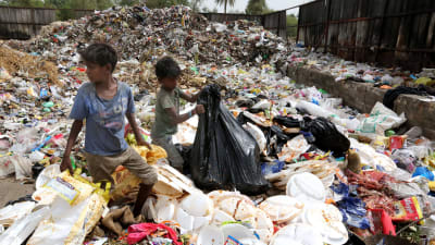 Indiska barn omgivna av avfallshögar