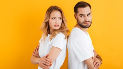 Ung man och kvinna står rygg mot rygg och blänger irriterat på varandra