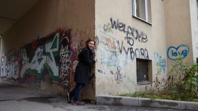 Anna Kortelainen Viipurissa syksyllä 2016. Rapistuneen seinän graffitissa lukee tekstit Welcome to Vyborg sekä Love.