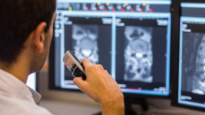 Läkare tittar på bilder från en MRI-undersökning och dikterar i en diktafon.