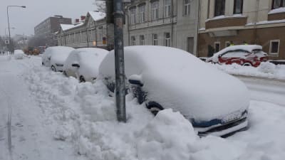 Tre bilar är helt insnöade längs en gata som plogats. Det har snöat 30 centimeter under natten.