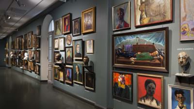 Massor med porträtt hänger på en lång vägg i Ateneum. En bild från samlingsutställning Historier inom finsk konst.