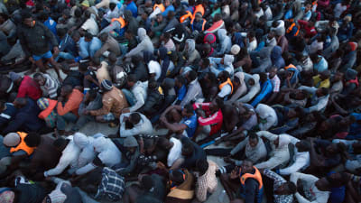 Flyktingar som den libyska kustbeavkningen har räddat ur Medelhavet väntar på att föras till interneringsläger
