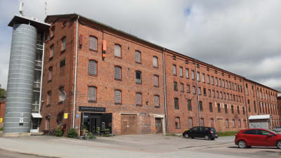 Barkers gamla fabrik är en lång röd tegelbyggnad med parkering framför.