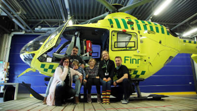Elina, Jasu, Jasse ja Adalmiina poseeraavat FinnHEMS-helikopterin edessä yhdessä ensihoitolääkäri Heini Harve-Rytsälän ja lentäjä Jonne Lundbergin kanssa.