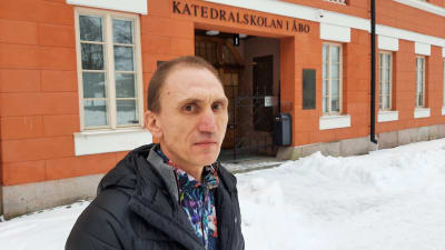 Herman Norrgrann, en man med svart dunjacka, står framför en orangebrun byggnad.