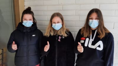 Matilda Tulla, Elsa Kottonen och Kiia Nurmi, tre flickor med munskydd visar tummen upp 