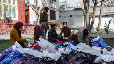 Frivilliga afghanska ungdomar sorterar kläder som ska doneras till bostadslösa i Afghanistan.