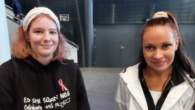 Aada och Sini, två unga damer med brunt och svart hår med hårband, tittar in i kameran.