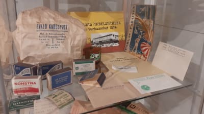 Påsar, kuvert och tändsticksaskar från gamla butiker i Pargastrakten, sparade i en vitrin i ett museum.