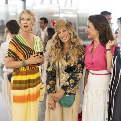 Miranda, Carrie och Charlotte i serien And just like that. De tre kvinnorna ler bland folk i en foajé. 