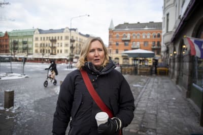 Kvinna med take away-mugg på Möllevångstorget i Malmö.