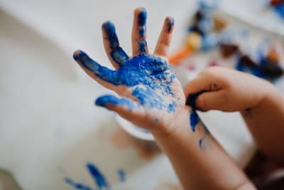 en liten glad hand som färgats blå av fingerfärg