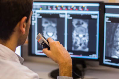 Läkare tittar på bilder från en MRI-undersökning och dikterar i en diktafon.