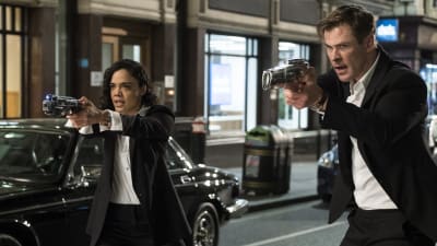 Agent M (Tessa Thompson) och Agent H (Chris Hemsworth) står med dragna vapen på gatan.