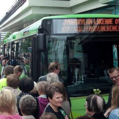 Ihmisiä vihreän bussin ympärillä.