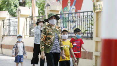 Kvinnor och barn på promenad i Hanoi på söndagen - alla utrustade med munskydd. 