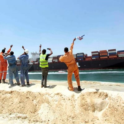 Egyptiläiset työntekijät vilkuttivat konttialukselle, joka kulki uudella Suezin kanavalla Ismailian kaupungissa Egyptissä 25. heinäkuuta.
