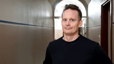 Man i svart tröja står i en korridor.