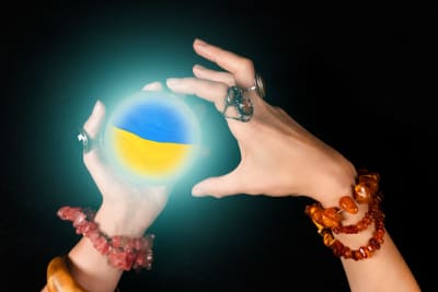 En häxa håller ett klot med Ukrainas flagga i sina händer.