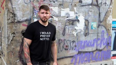 Porträtt på Christian Weissgerber framför en vägg fylld av graffiti.