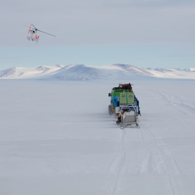 En helikopter flyger över isen i Antarktis. 