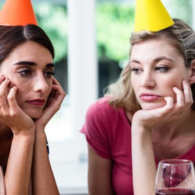 Två uttråkade unga kvinnor med partyhattar