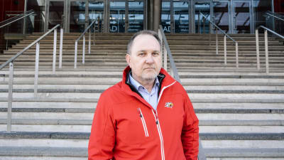 Medeleålders man i röd jacka med Vasa sports logo står vid en bred trappa utomhus.