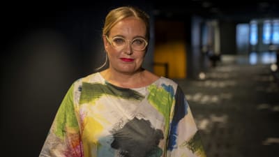 Närbild på filmregissören Saara Saarela som ser rakt in i kameran medan bakgrunden är suddig.