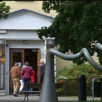 Ihmiset menevät keltaiseen rakennukseen sisälle.