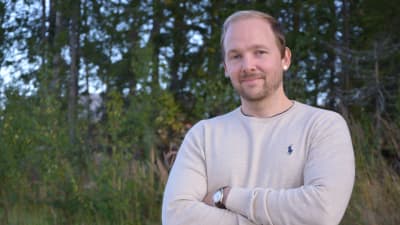 Man med skägg ser in i kameran med ett litet leende.